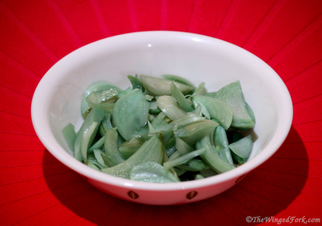 Blue pickled onion in a white bowl on a red tablecloth.