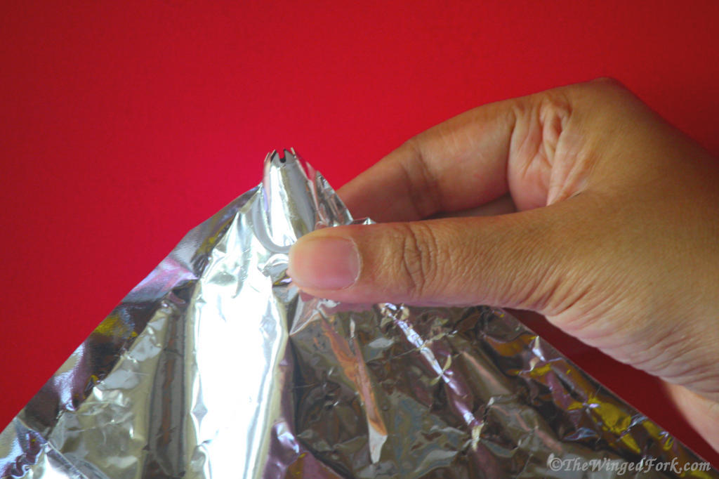 A hand holding a nozzle in a foil.