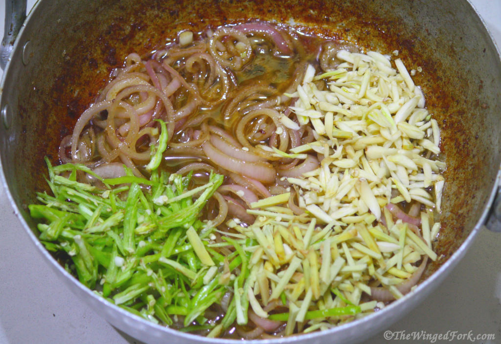 Chopped chilies, garlic annd ginger added to onions frying in a kadai.