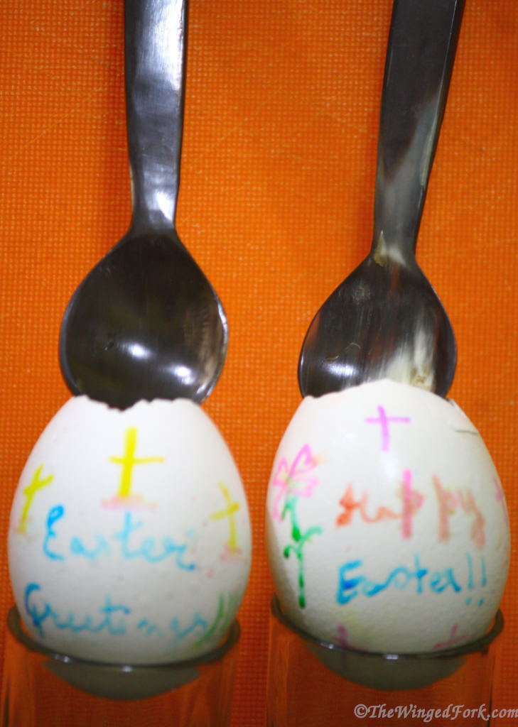 A decorated egg shells with spoons on top.