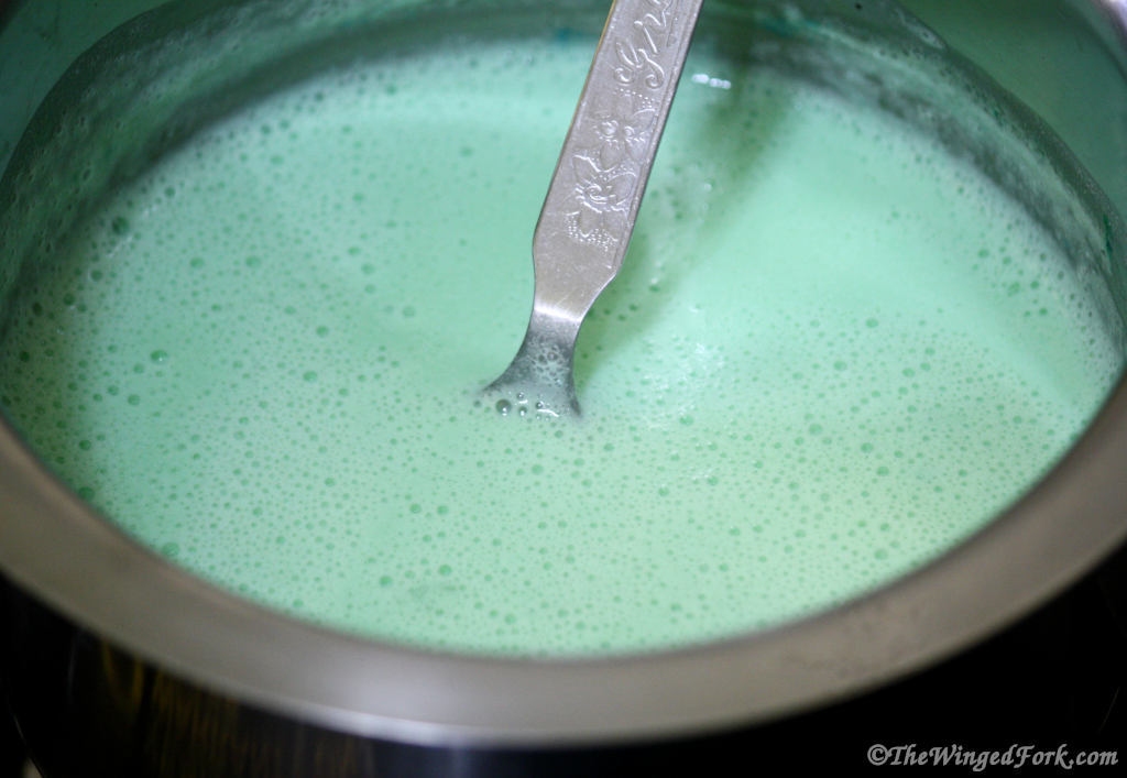 Green blancmange ready in a vessel with a spoon.