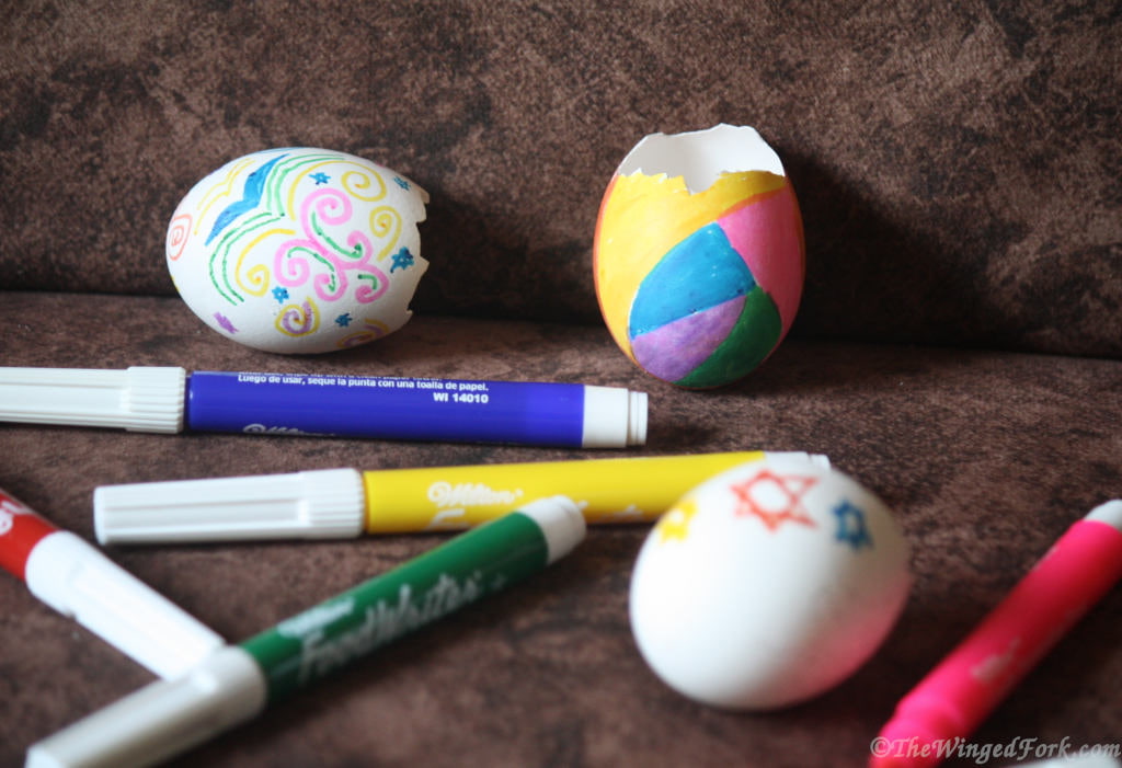 Decorated egg shells next to colour pens.