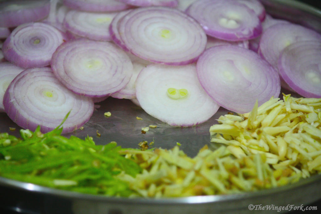 Cut onion slices and also cut chilies, ginger and garlic.