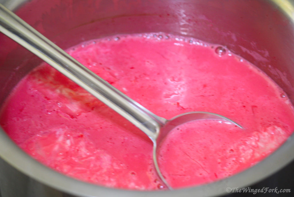 A spoon in pink milk in a vessel.