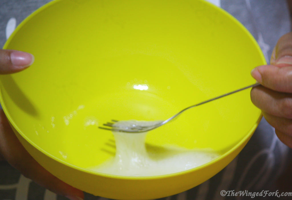Egg white with a fork in a yellow bowl.