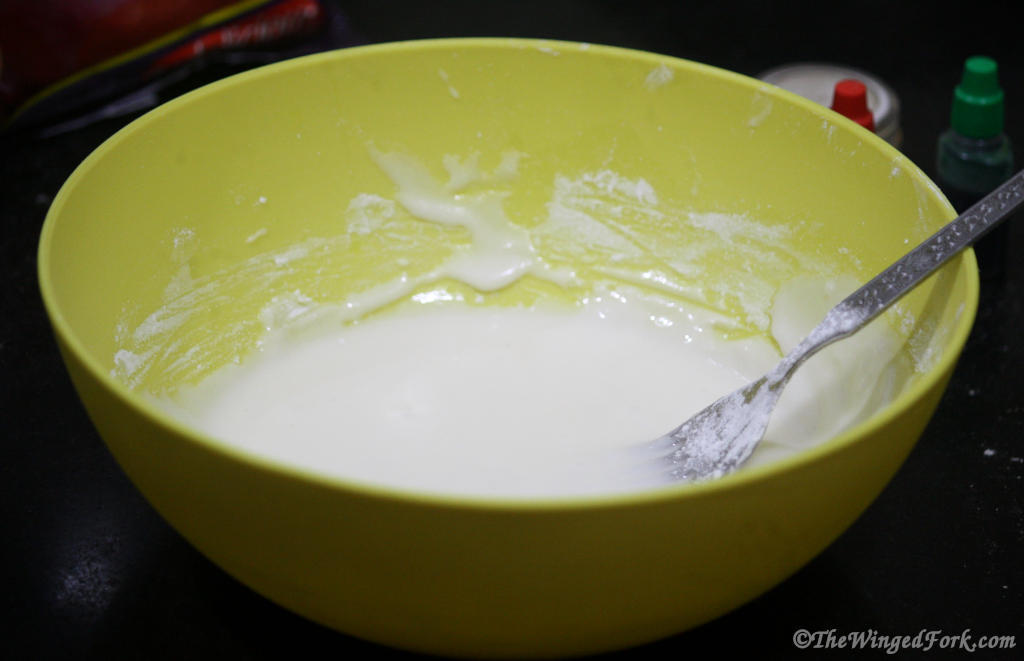 A bowl of white icing with a fork in it.
