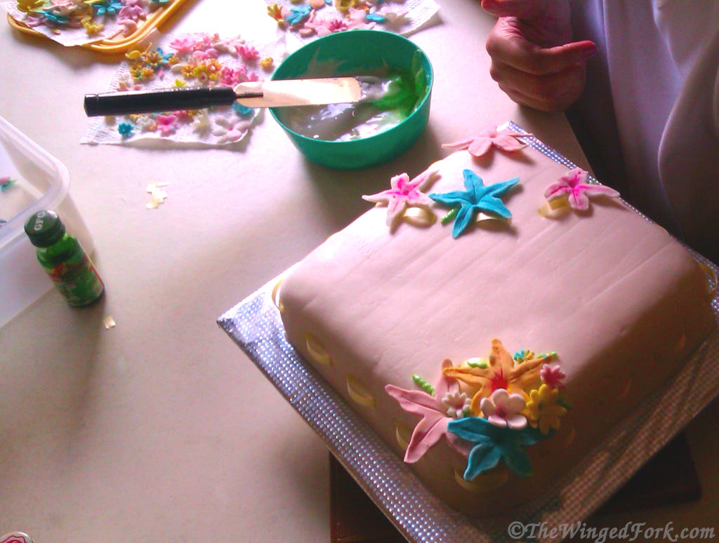 Royal icing being used to stick sugar craft flowers on a cake.