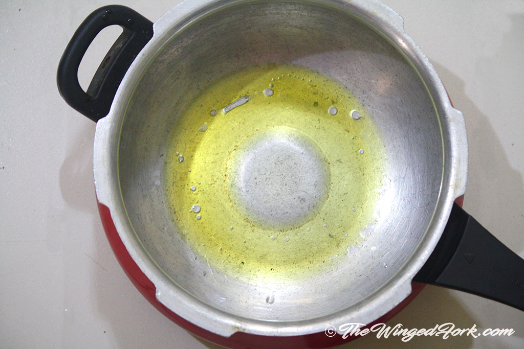 Add oil to a pressure cooker.