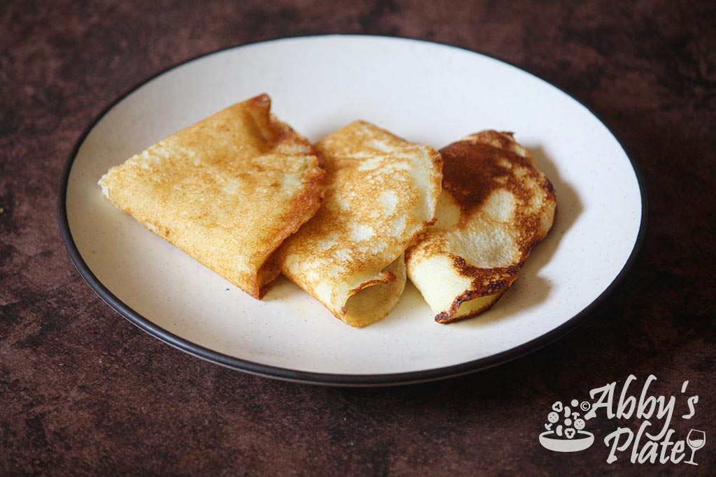 East Indian gluten free rice crepes called chitaps folded in triangles on a beige plate.