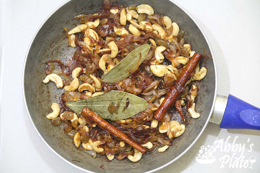 The fried onions and cashewnut mix in a frying pan.