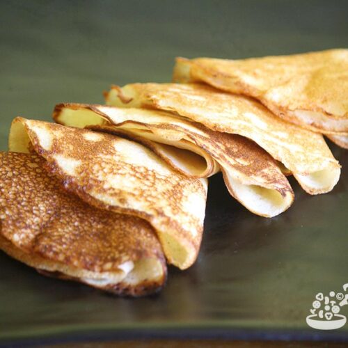 East Indian gluten free rice crepes called chitaps folded in triangles on a black tray.