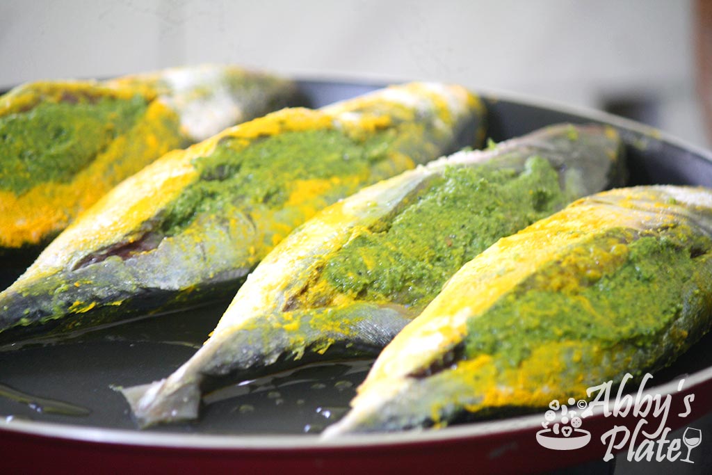 Stuffed green mackerels lines on a frying pan.