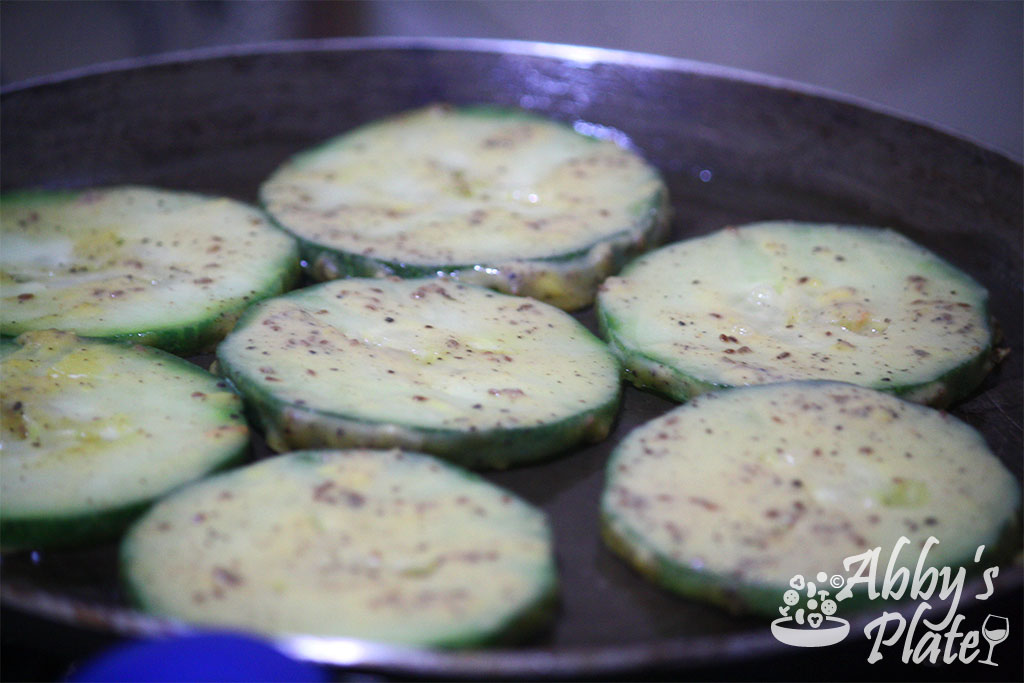 Zucchini being shallow fried in a pan.