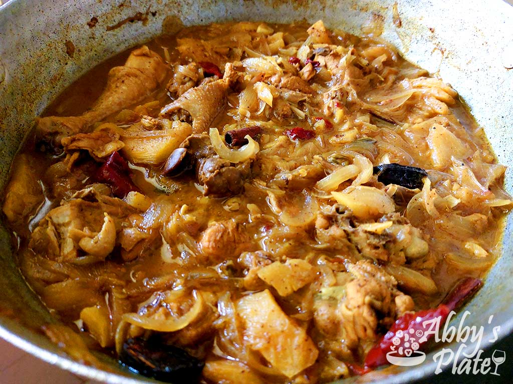 Curry in a kadai with onions, chicken, red chilies and spices.