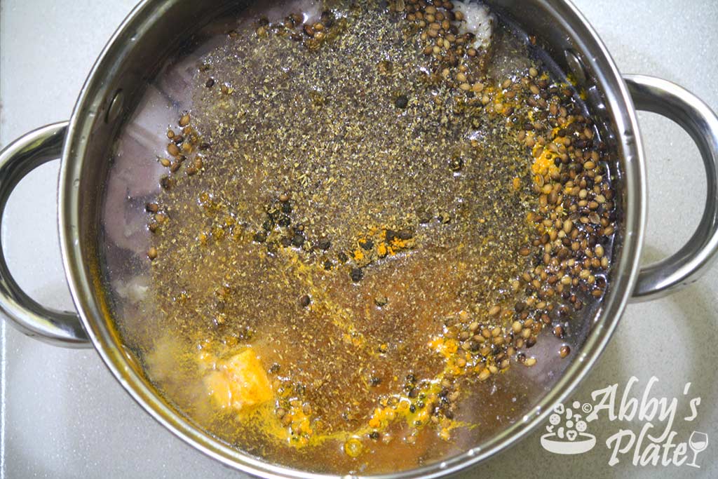 Spices floating on the water in the steel pot.
