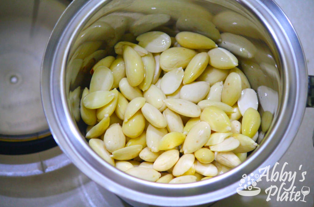 Raw skinned almonds in a mixer grinder jar.
