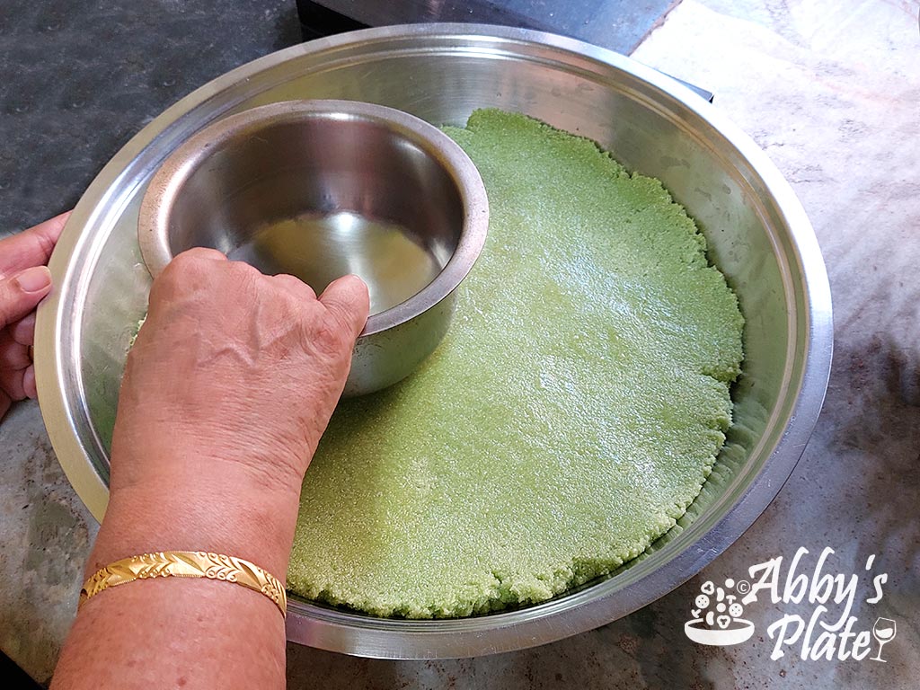 Mom flattening the hot sojee mix with the underside of a buttered pot.
